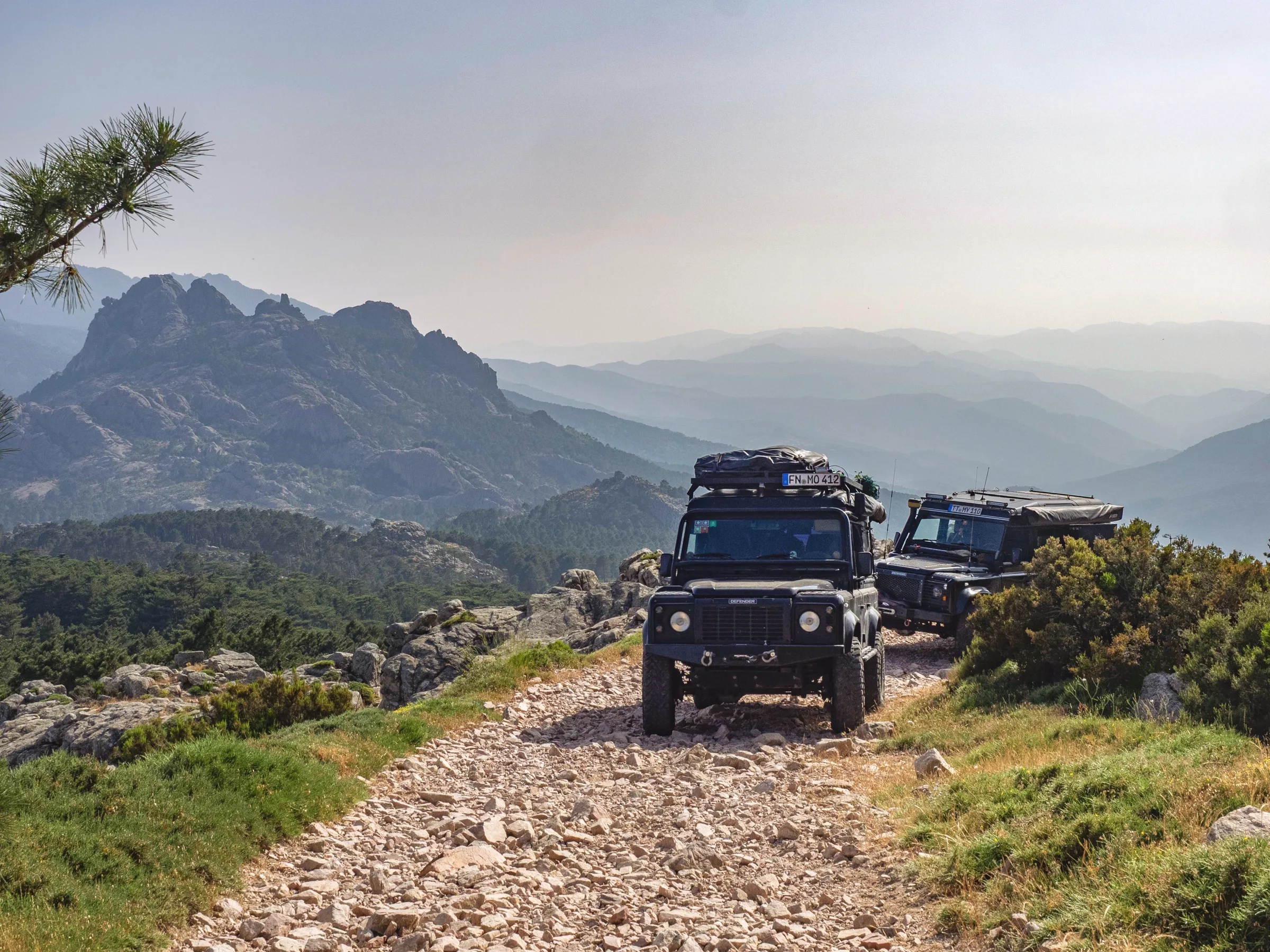 Two Land Rover Defenders on a rocky mountain track high above the mountains of Corsica