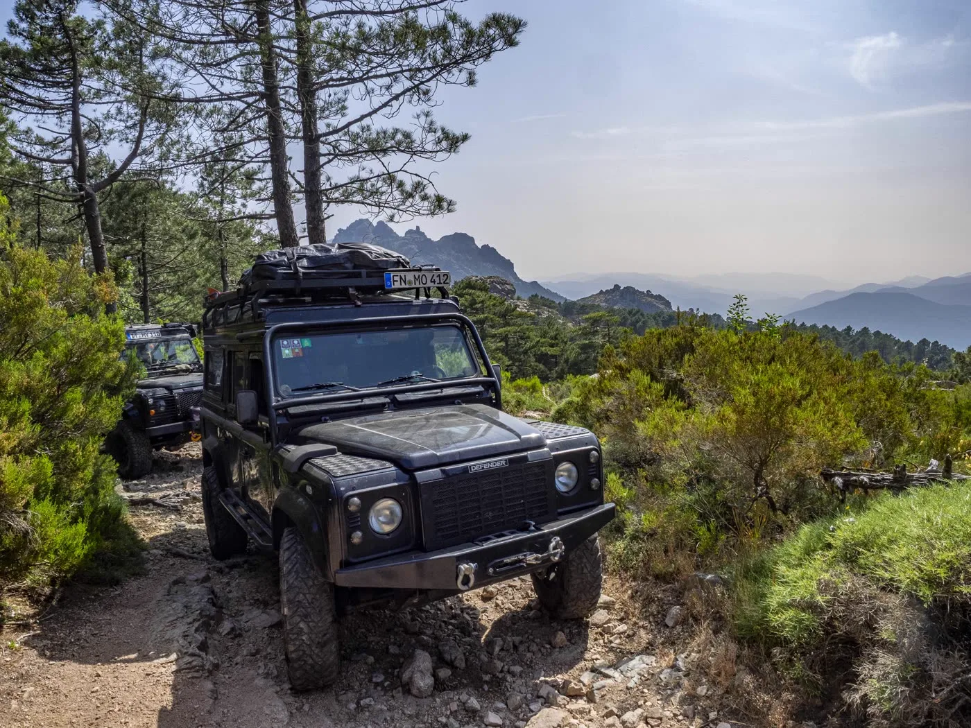 Defender on a mountain path with a view across the mountains