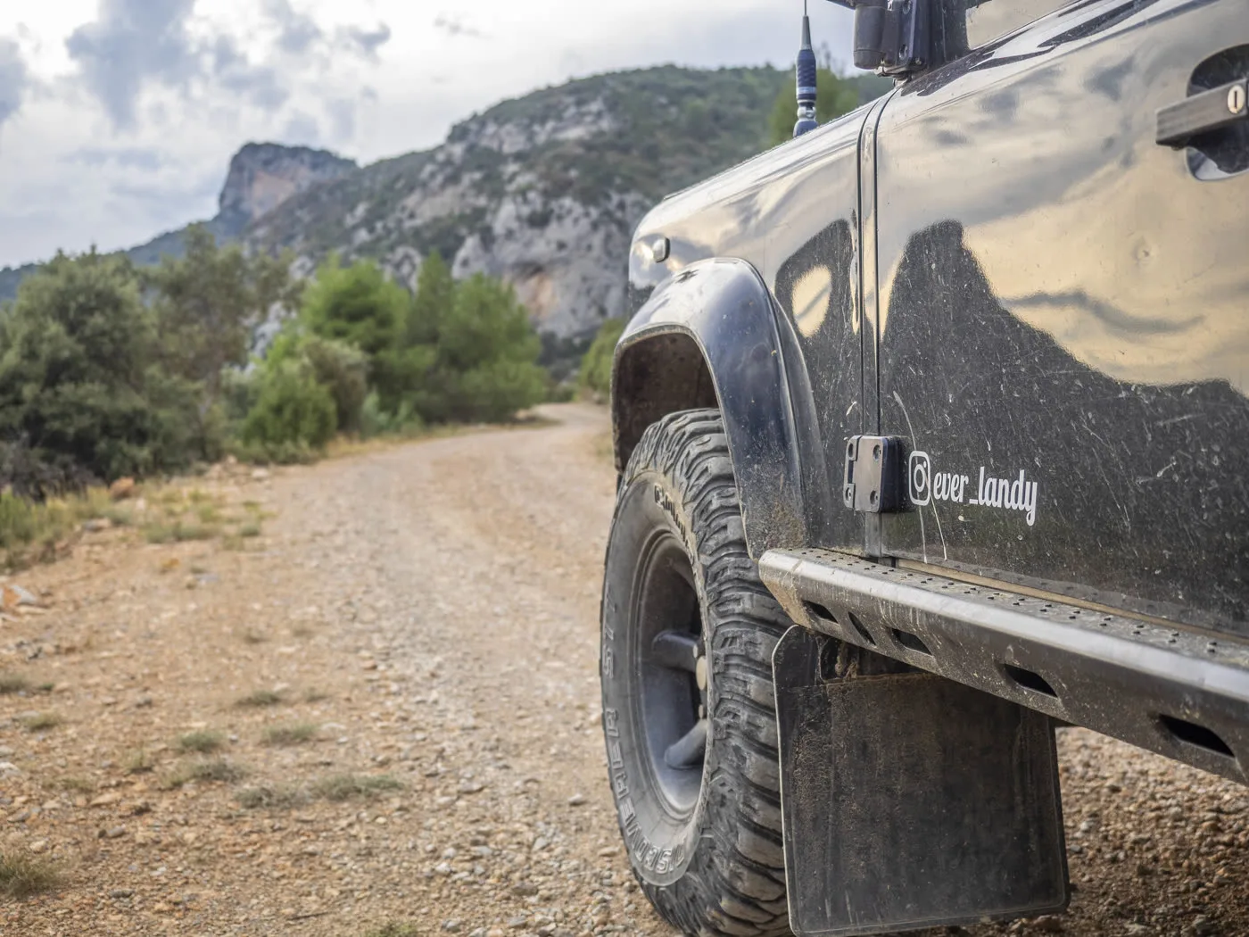Side view of a Defender on a gravel track in a gorge